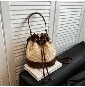 Detail of contrasting straw and brown leather bucket bag on a minimalist white table