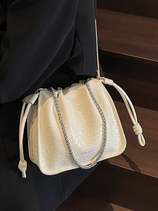 Chic beige textured bucket bag with drawstring closure and stylish silver chain strap