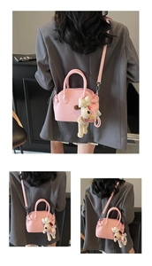 Detailed macro view of pink lychee pattern faux leather shell bag with plush puppy pendant