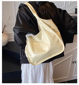 Close-up of cream white tote bag with glossy oily wax leather texture and wide strap