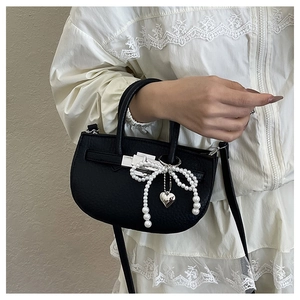 Detail of black litchi pattern bucket bag with pearl bow and silver heart pendant