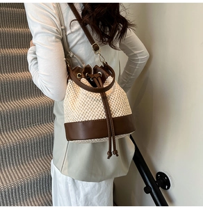 Detail of a contrast woven straw bucket bag with leather drawstring and gold hardware