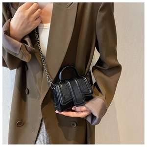 Détail d'un mini sac à main noir effet croco avec une bandoulière en chaîne métal