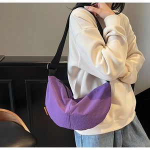 Detail of purple nylon dumpling bag with orange tag and adjustable strap