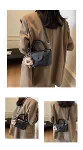 Detail of vintage black leather handbag featuring a plush lion charm and crossbody strap