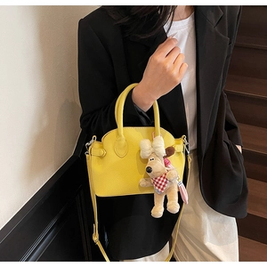 Detail of yellow lychee texture shell bag with a cute plush dog charm accessory