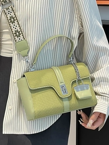 Grüne Lederhandtasche mit Ethno-Gurt und Mini-Anhänger, getragen von einem Model