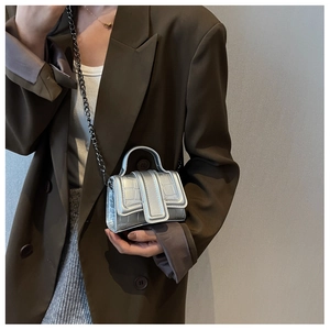 Détail du mini sac bandoulière argenté à texture crocodile et chaîne sur le mannequin