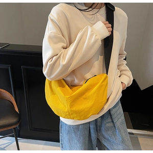 Side view of a yellow dumpling-shaped crossbody bag worn by a model in a casual setting