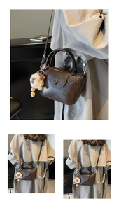 Detail view of brown vintage leather handbag with white sheep pendant charm accessory