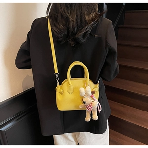 Close-up of a bright yellow litchi leather shell bag with a cute puppy charm detail