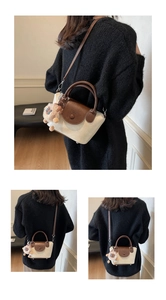 Detail of mini bucket bag with leather flap and cute plush lion charm accessory