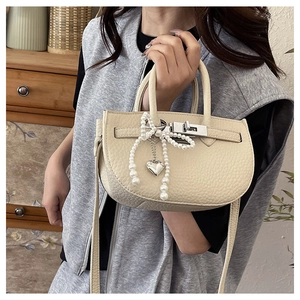 Detail of lychee pattern leather bucket bag with pearl bow and silver heart charm