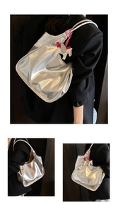 Detail of silver metallic tote bag with smooth texture and cute white horse charm accessory