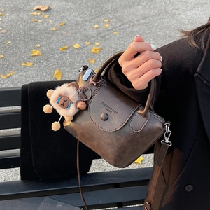 Sac à main rétro marron chic avec breloque en peluche dans un décor d'automne avec feuilles