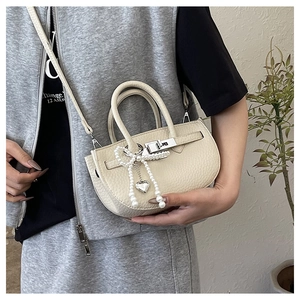 Detail of off-white lychee pattern bucket bag with pearl bow and silver twist lock