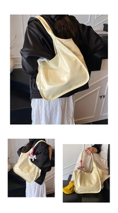 Detail of glossy beige tote bag featuring a decorative white horse charm and wide strap