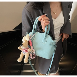 Detail of light blue litchi pattern shell bag with cute plush puppy charm accessory