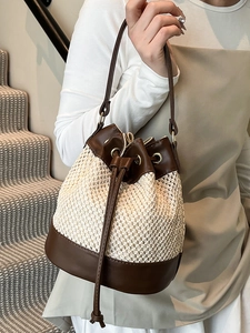 Contrast straw woven drawstring bucket bag with brown leather trim and shoulder strap