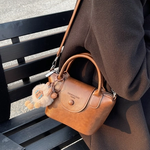 Brown vintage leather crossbody bag with top handle and cute plush charm on long strap