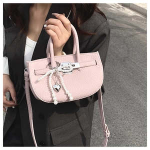 Detail of pink lychee texture bucket bag with heart pearl charm and silver lock buckle