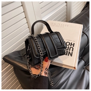 Gros plan du mini sac à main noir à motif crocodile avec chaîne métallique et détails soignés
