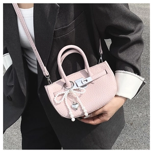 Detail of pink lychee leather bucket bag with pearl bow and heart metal charm