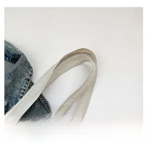 Detail of reinforced wide canvas handles with double-line stitching on a tote bag
