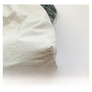 Detailed macro view of white nylon tote bag with natural wrinkled texture and red logo