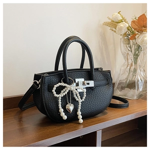 Detail of black lychee grain leather bucket bag with pearl bow and heart charm