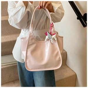 Close-up of pink wax leather tote bag with a white unicorn charm and metal brand logo