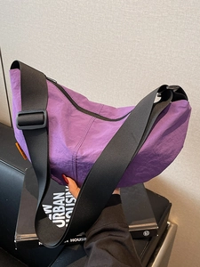 Purple nylon crescent moon crossbody bag with adjustable wide strap and orange label detail