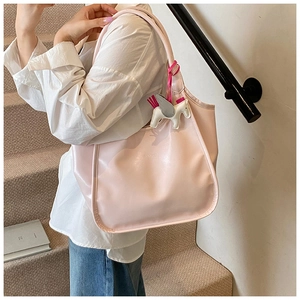 Detail of light pink faux leather tote bag with elegant pegasus charm on long straps
