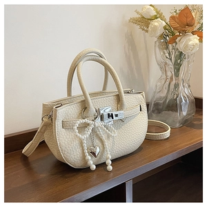 Detailed view of beige lychee pattern leather bag with pearl bow and heart charm