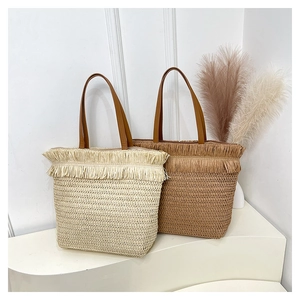 Detail view of woven straw tote bags with long fringe tassels in beige and tan colors