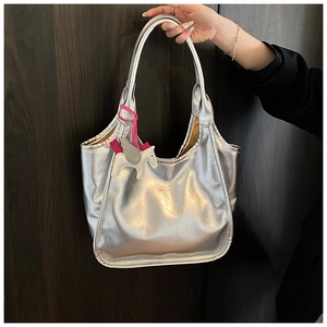 Macro detail of silver oil wax texture tote bag with a white winged horse charm