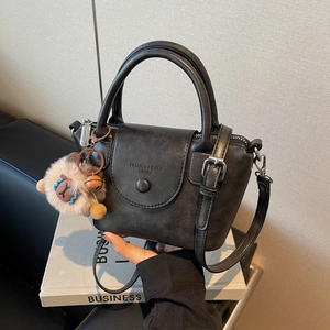 Détail du sac à main trapèze noir avec pendentif lion en peluche et texture cuir