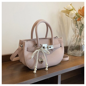 Close-up of pink litchi grain leather bucket bag with pearl bow and heart charms