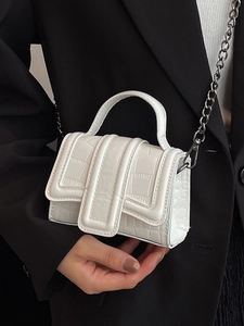 Mini sac à main blanc à texture crocodile et chaîne argentée porté sur une veste de costume