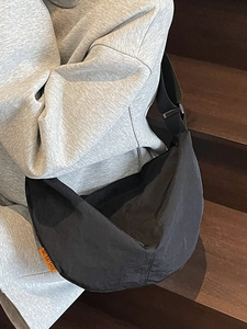 Minimalist black crescent crossbody bag in lightweight nylon fabric for casual commute