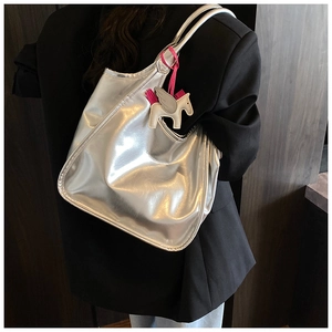 Detail shot of a silver metallic tote bag featuring a winged horse charm and glossy finish
