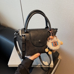 Détail d'un sac à main noir en cuir mat vintage avec breloque agneau et bandoulière
