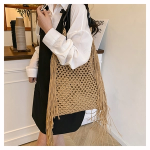 Close-up of woven hollow mesh tote bag featuring long fringes and black leather shoulder strap