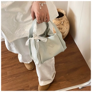 Detail of mint green lychee grain leather bucket bag with lace bow and brand logo