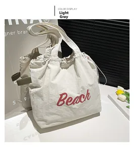 Detail of light grey nylon tote bag with red Beach text and drawstring closure