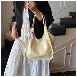 Detail of light beige tote bag with wax leather texture and decorative horse charm