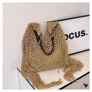 Detail of bohemian woven tote bag with long tassels and black leather handles