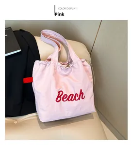 Close-up of pink nylon beach tote bag with red Beach lettering on a soft cream sofa