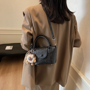 Détail du sac à main rétro noir avec pendentif lion en peluche et cuir synthétique grainé