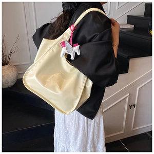 Macro shot of glossy cream wax-leather tote bag texture with a cute pony charm